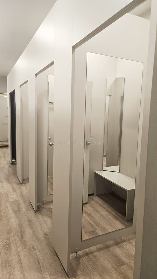 Fashion store fitting room corridor with mirror-fronted doors and clean lighting