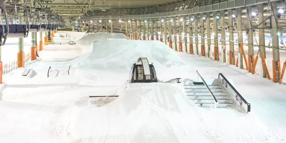 Indoor ski slope training obstacles and race course features arranged on compacted snow surface under bright overhead lighting